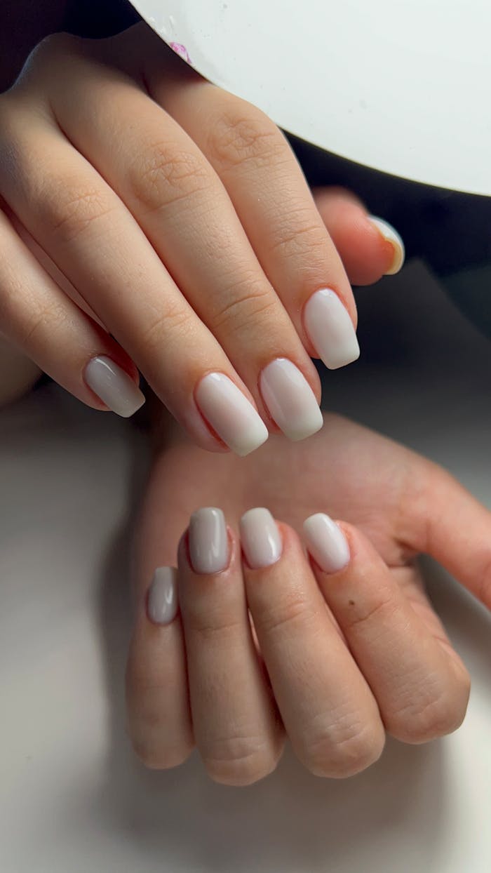 Home Elegant close-up of hands with soft pink nail polish under lamp light. Perfect for beauty and skincare themes.