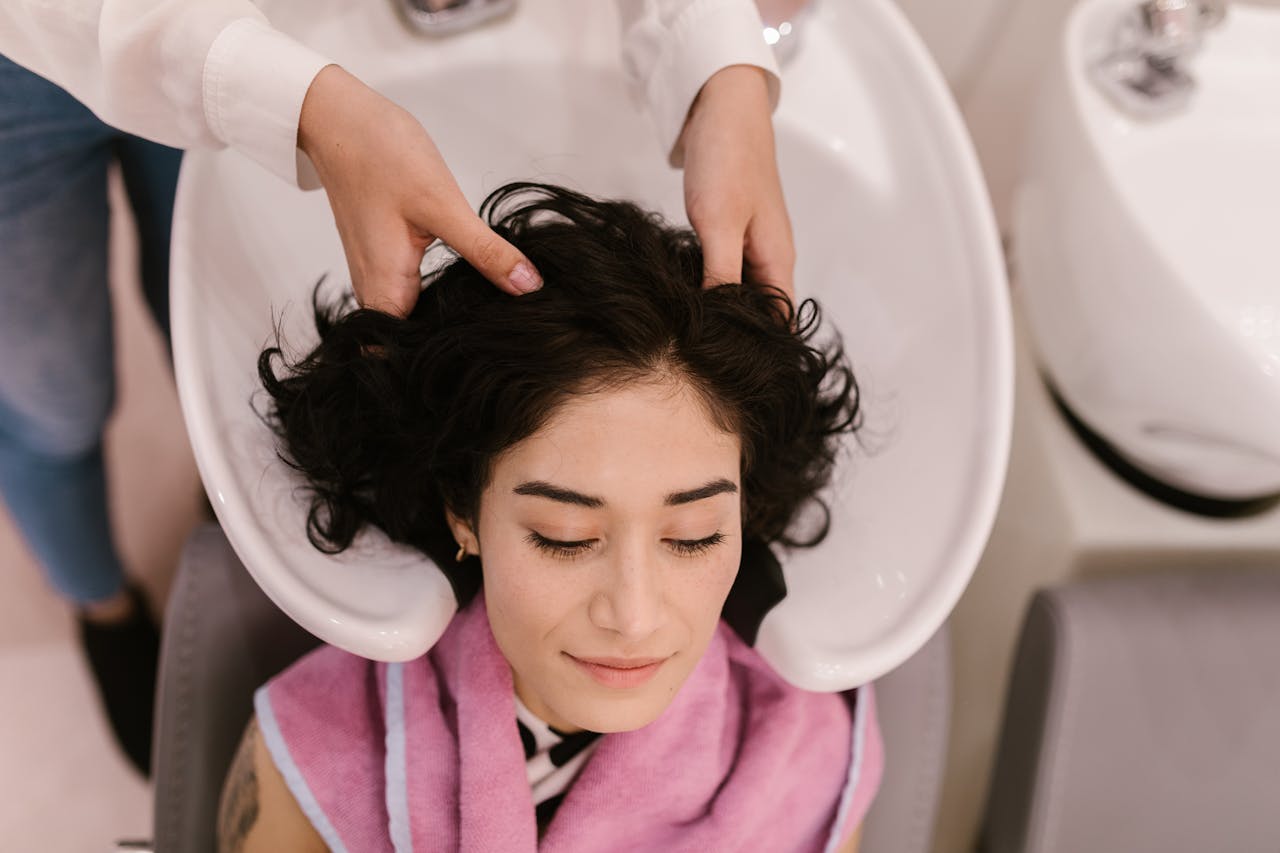 A serene woman enjoys a hair wash and massage at a contemporary hair salon.